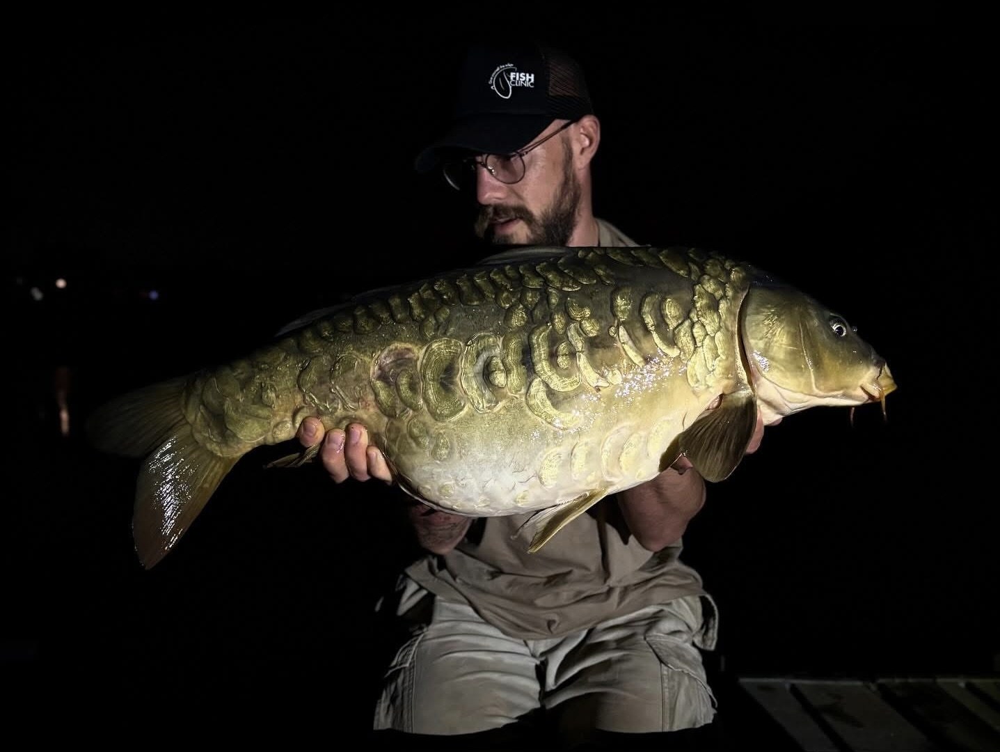 Big mirror carp held at night under torchlight
