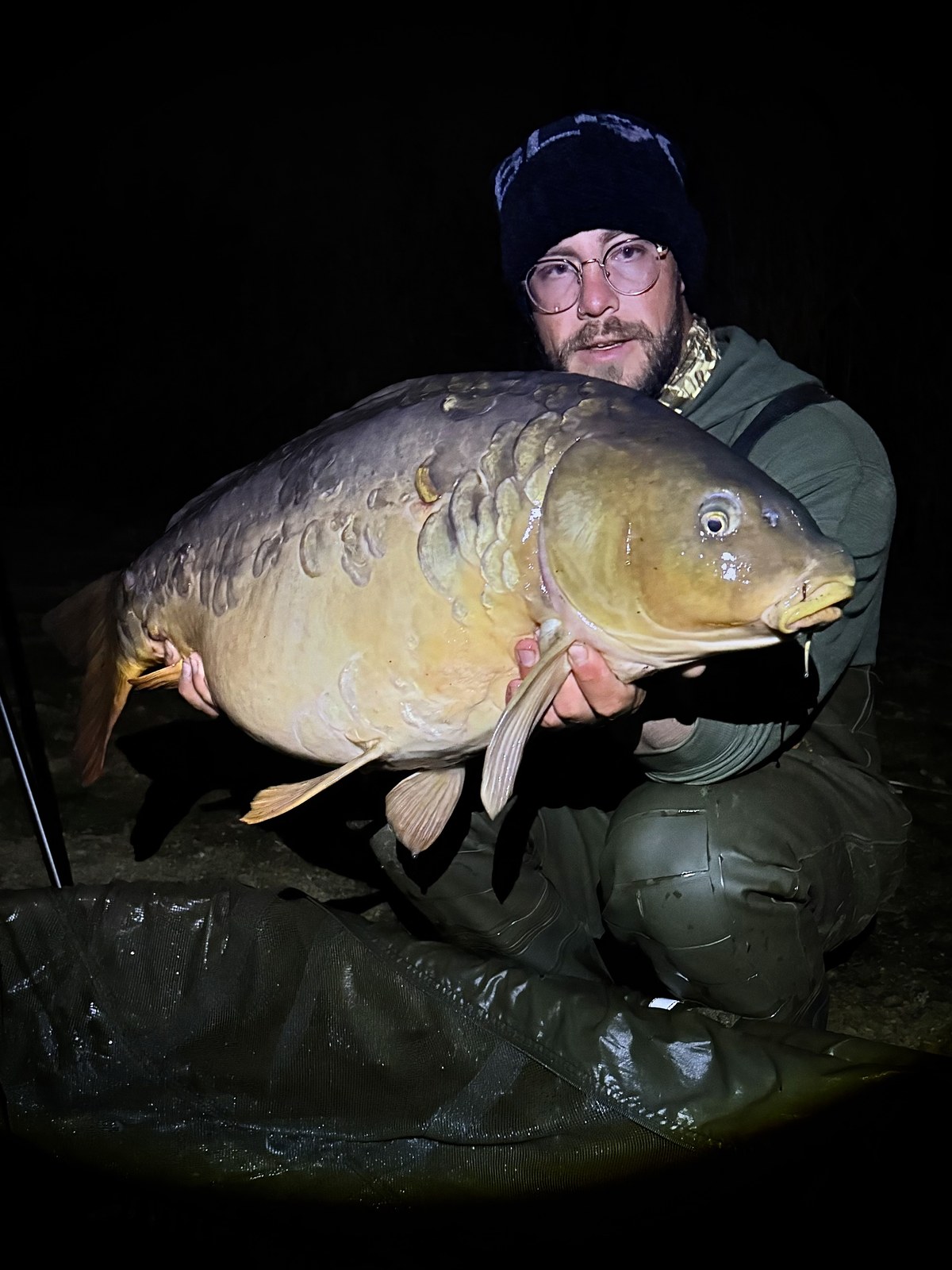 A friend holding a big common carp after dark
