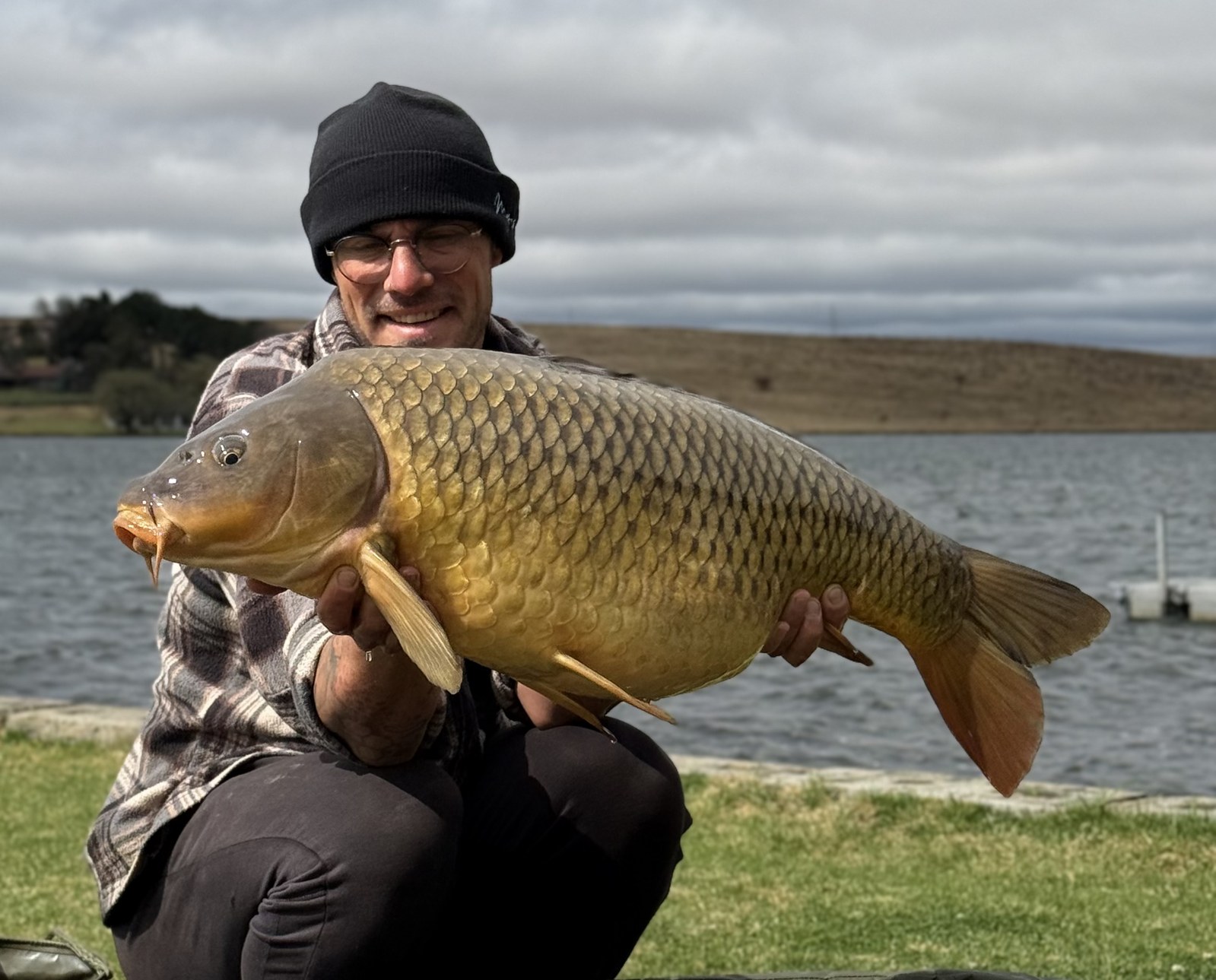 Angler with a big common carp on an overcast day